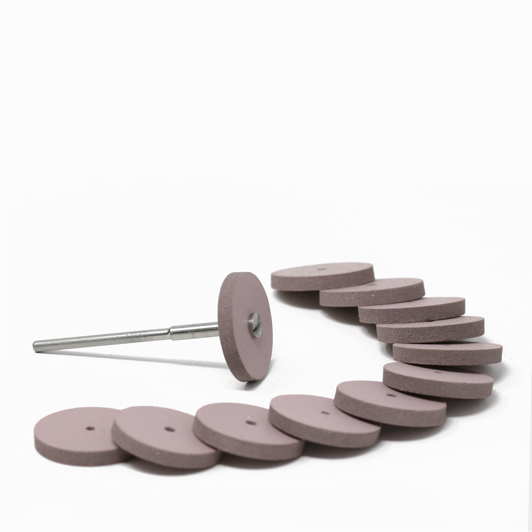 Set of twelve pink polishing wheels on a white background; one has a mandrel attached.